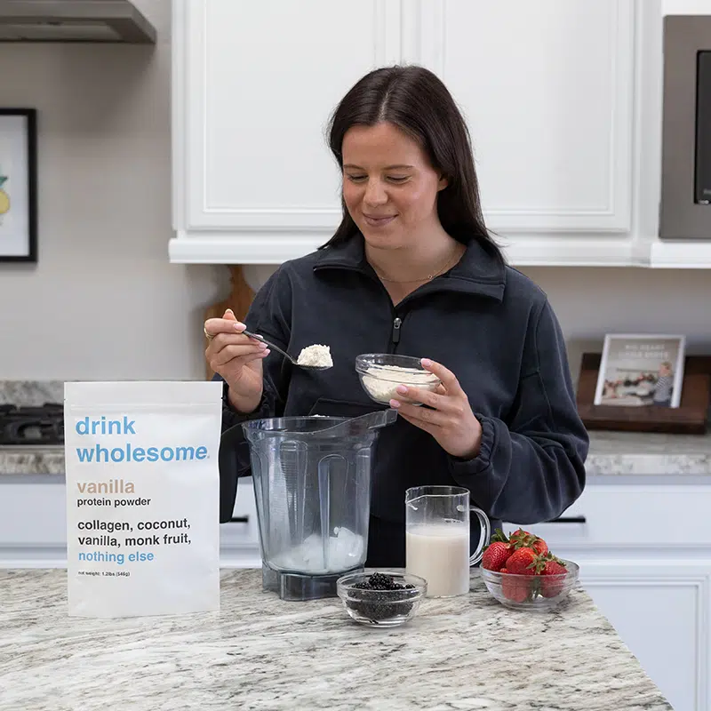 drink-wholesome-vanilla-collagen-protein-powder-shake a woman making a protein shake with drink wholesome protein powder