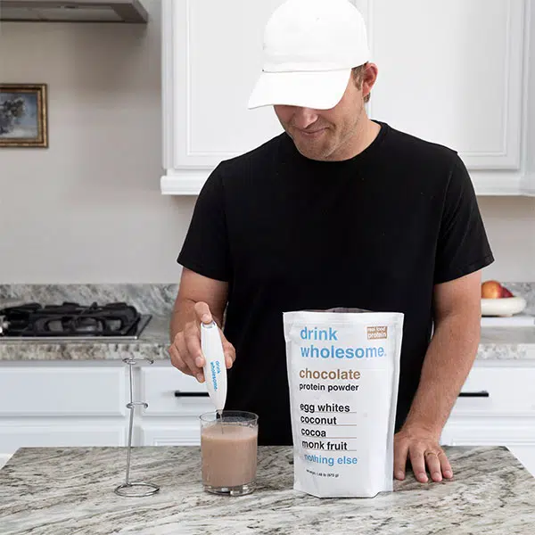 a man making a protein shake with a drink wholesome electric mixer