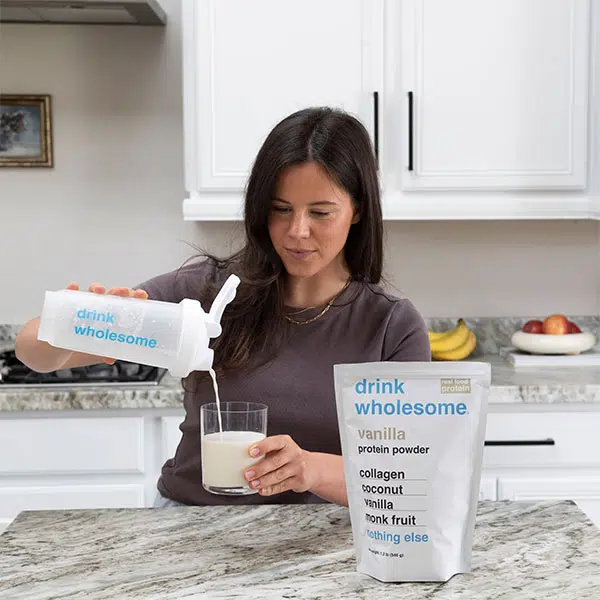 a woman making a protein shake with a drink wholesome shaker bottle
